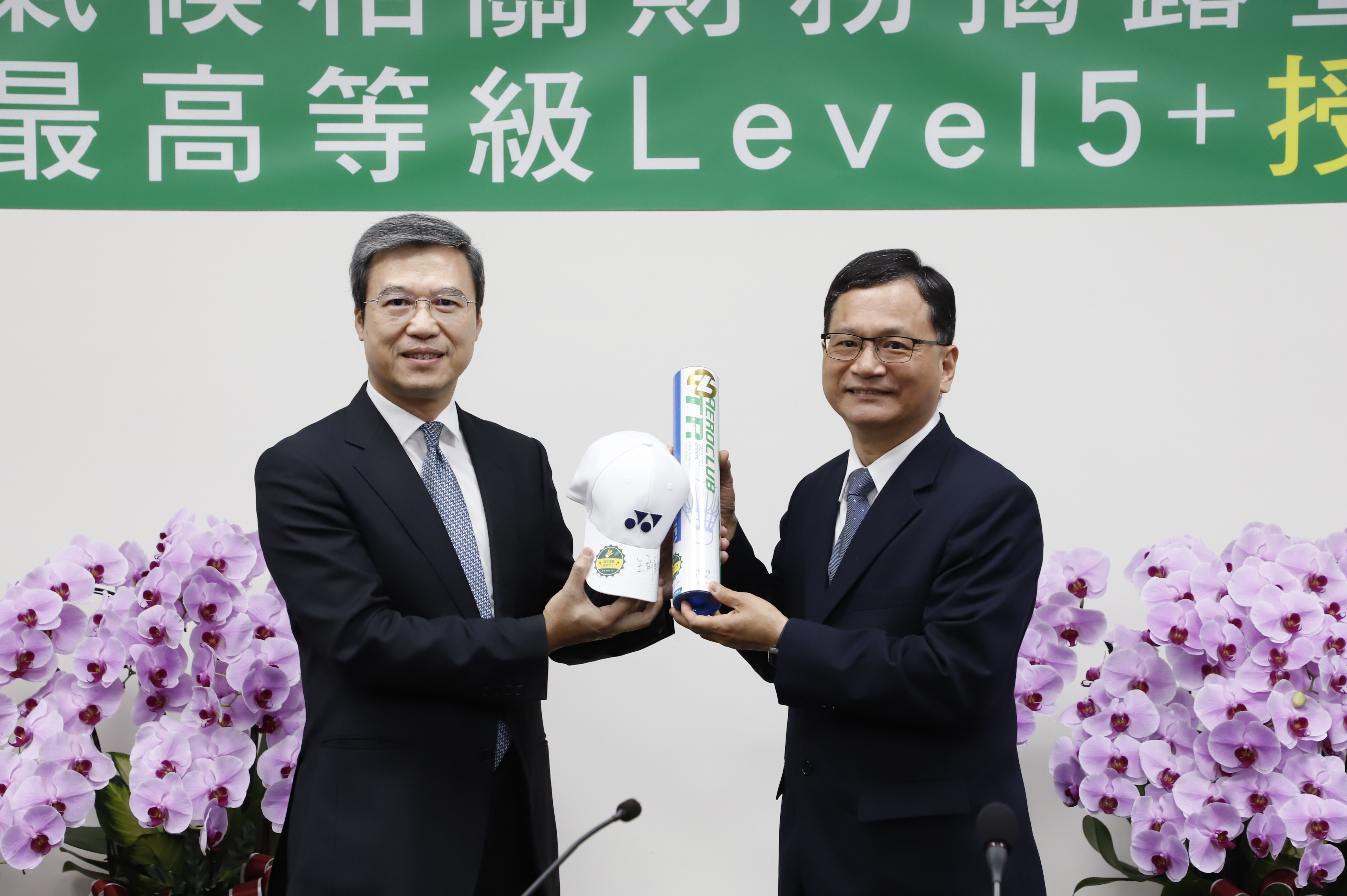 Ying-Ming Ho (right), Chairman of Land Bank of Taiwan, presents a signed cap from Chi-Lin Wang, a gold medalist from the Land Bank of Taiwan badminton team, to Shu-Sheng Pu (left), Managing Director of BSI Northeast Asia.