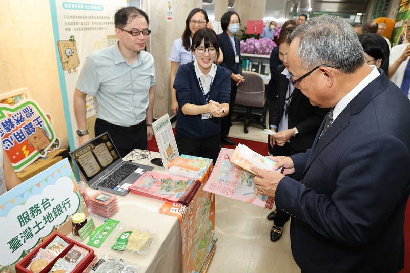 本行80周年，行史檔案展結合公益市集活動，本行總經理張志堅(右)聆聽同仁說明行史中英雙語摺頁設計，接軌國際客群。