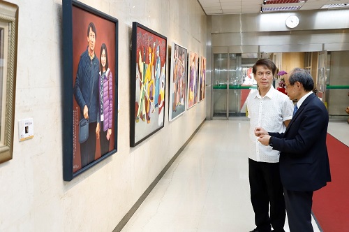 本行主任秘書劉文吉（右）聆聽油畫大師張朝凱（左）導覽其作品。