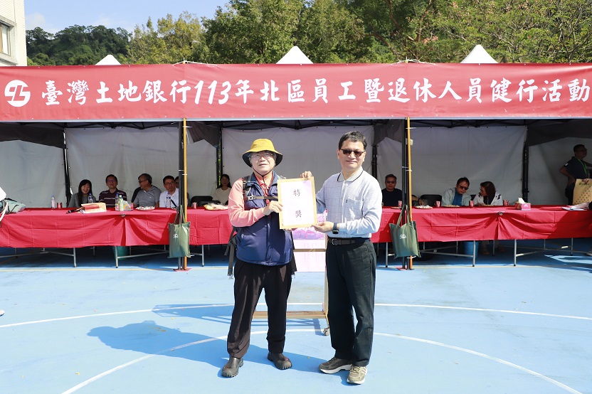 本行董事長何英明(右)與中獎同仁合影，獎品為百貨公司禮券。