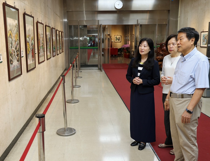 水墨藝術家廖仁彬（右）為本行副總經理蔡慈瑛（左）、本行主任秘書鄭瑟琴（中）導覽其畫作。